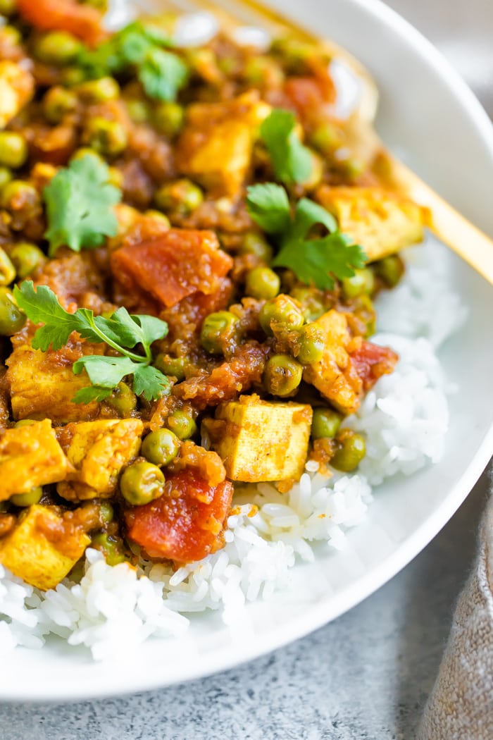 Tofu cooked in tomatoes and peas served over a bowl of rice. Topped with cilantro.