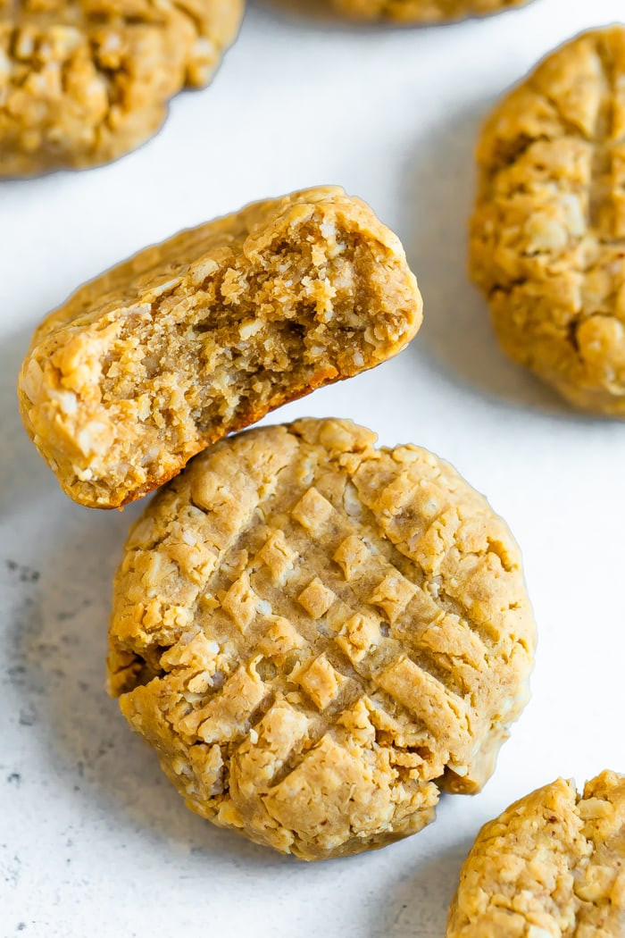 Two peanut butter protein cookies. One has a bite taken out of it.