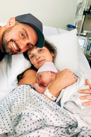 Couple smiling and holding their newborn baby girl in the hospital.