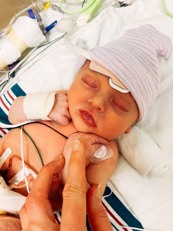 Mothers hand holding the arm of her new born baby girl at the hospital.