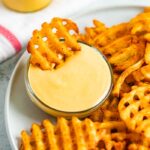 Waffle fry being dipped into homemade Chick-Fil-A Sauce.