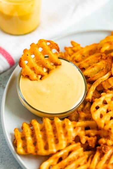 Waffle fry being dipped into homemade Chick-Fil-A Sauce.