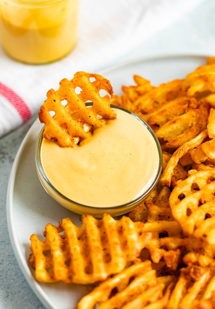 Waffle fry being dipped into homemade Chick-Fil-A Sauce.