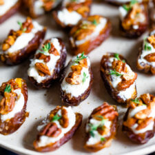 Plate with goat cheese stuffed dates, topped with chopped pecans and fresh thyme.