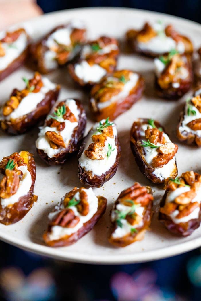 Plate with goat cheese stuffed dates, topped with chopped pecans and fresh thyme.