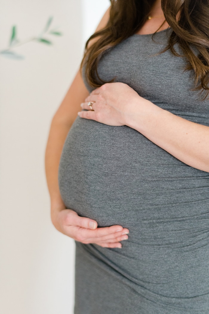 Up close shot of pregnant belly with woman's hands around it. 