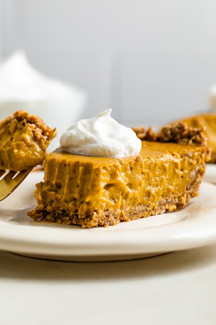 Slice of vegan pumpkin pie topped with whipped cream.