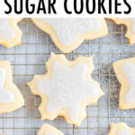 Snowflake and star cut-out cookies on a cooling rack decorated with white icing and sprinkles.