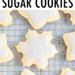 Snowflake and star cut-out cookies on a cooling rack decorated with white icing and sprinkles.