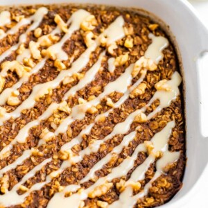 Baking dish with gingerbread baked oatmeal drizzled with frosting.