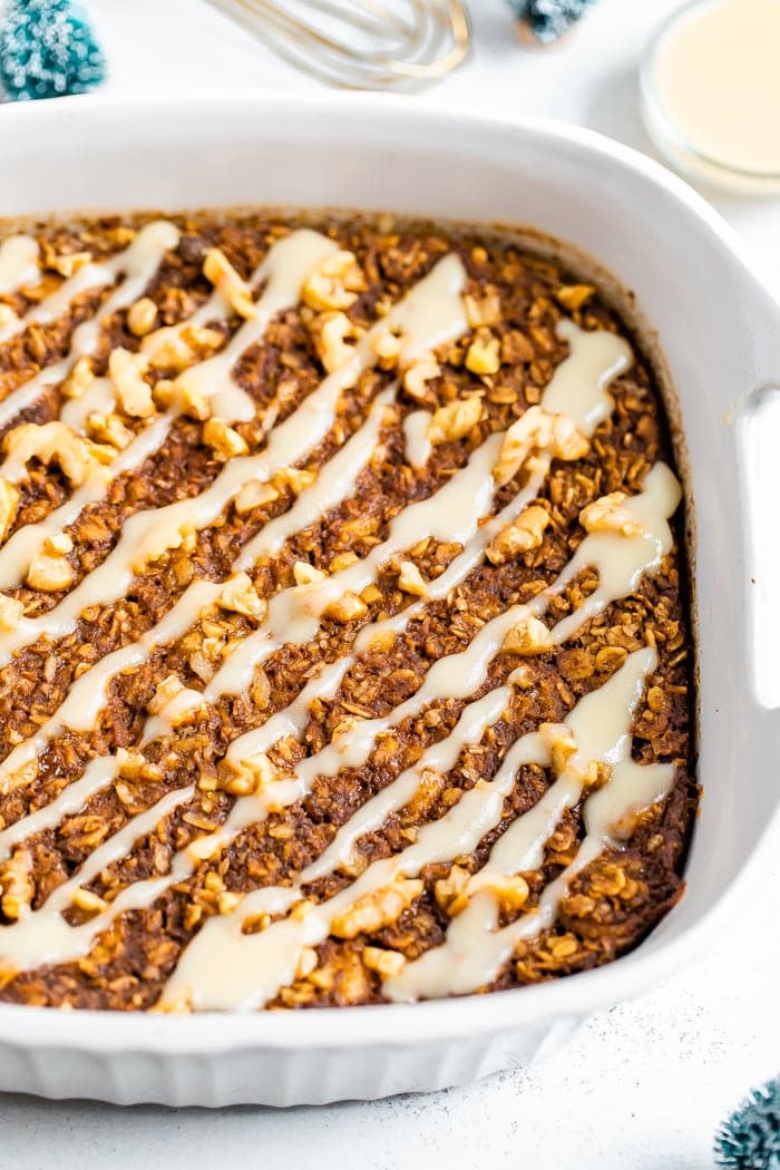 Baking dish with gingerbread baked oatmeal drizzled with frosting.