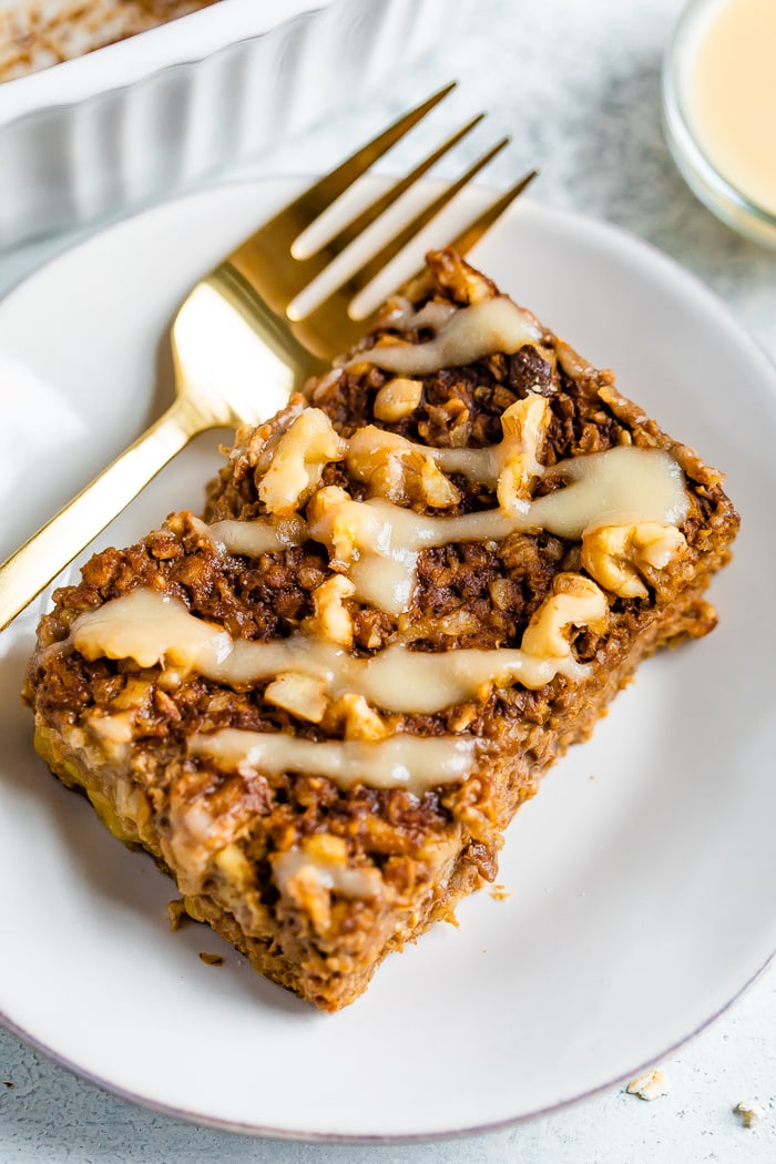 Slice of gingerbread baked oatmeal with frosting and a fork on a plate.