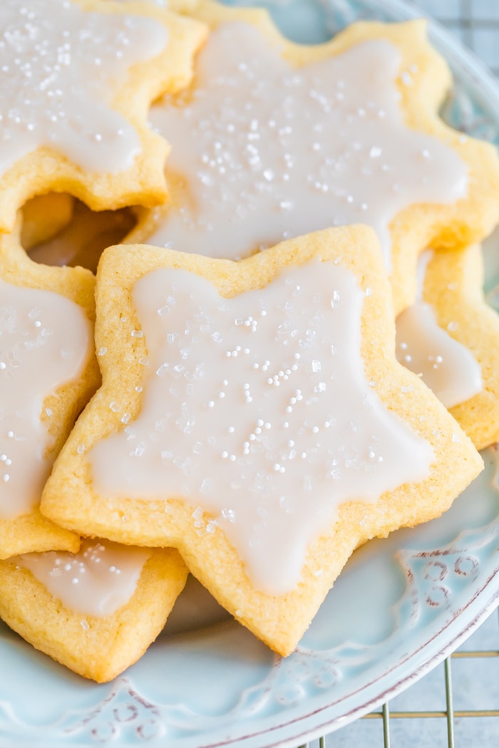 Plate of star and snowflake cut-out cookies with white icing and sprinkles.