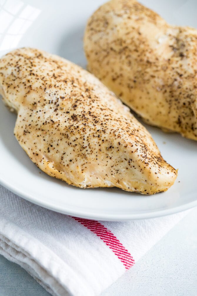 Two slow cooker cooked chicken breasts seasoned with salt and pepper.