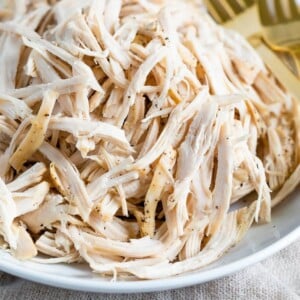 Plate with shredded chicken and two forks.