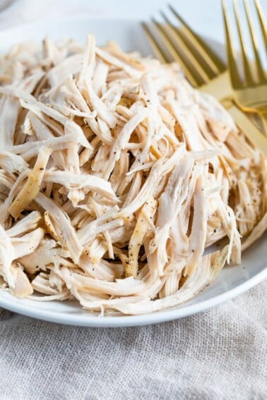 Plate with shredded chicken and two forks.