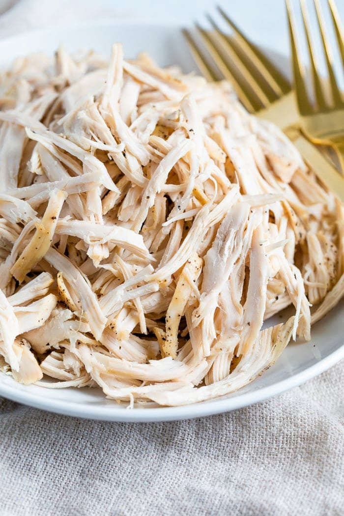 Plate with shredded chicken and two forks.