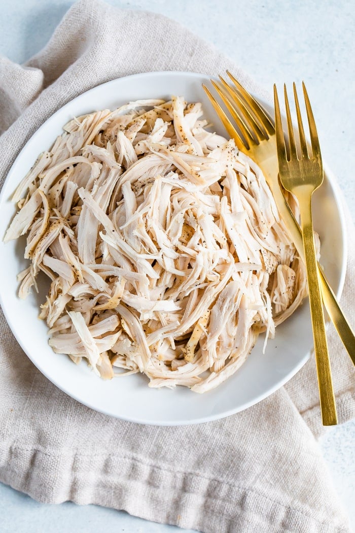 Plate with shredded chicken and two forks.