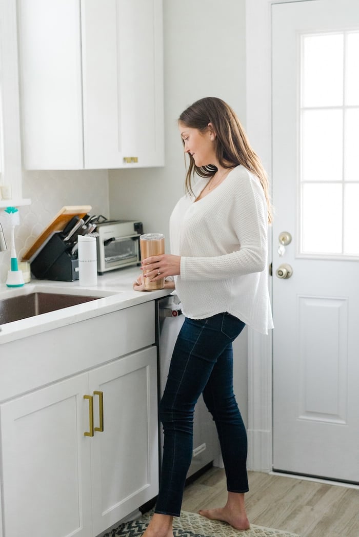 Woman in kitchen wearing Willow breast pump. 