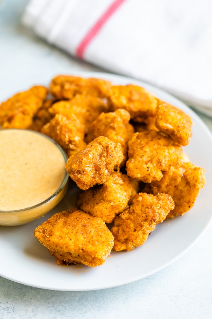 A plate piled with healthy baked chicken nuggets and honey mustard sauce.