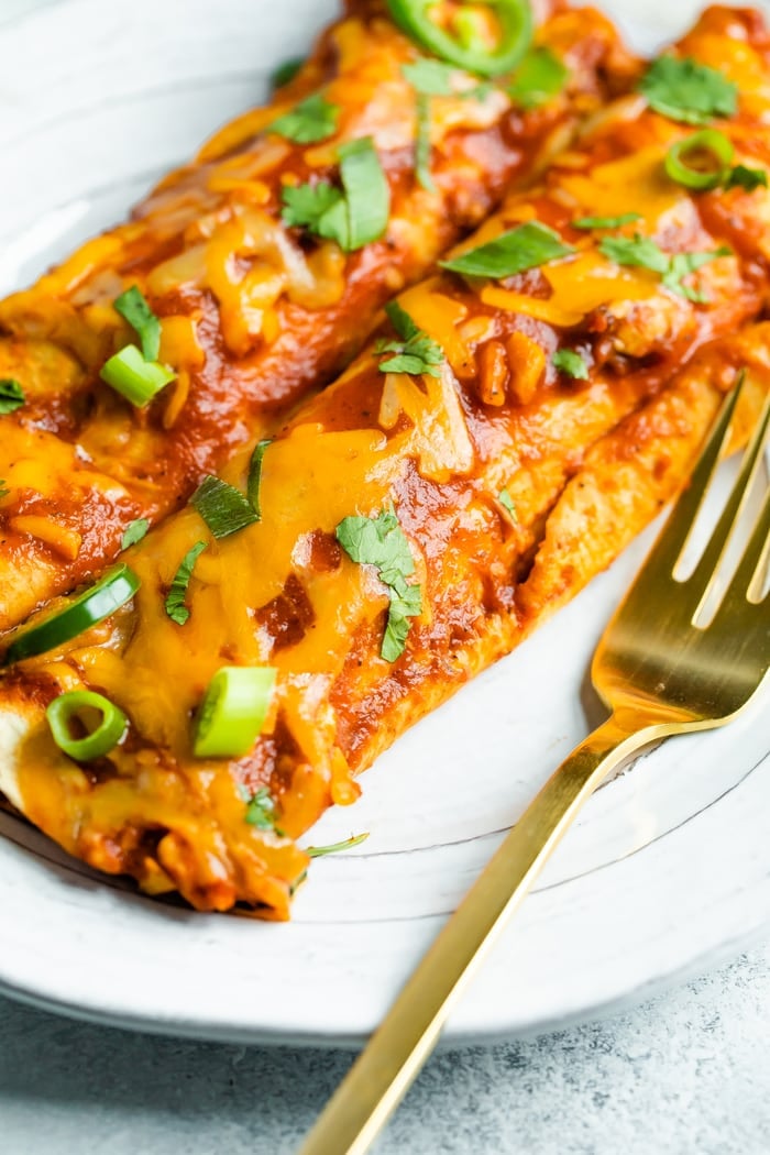 Two cheesy chicken enchiladas on a plate.