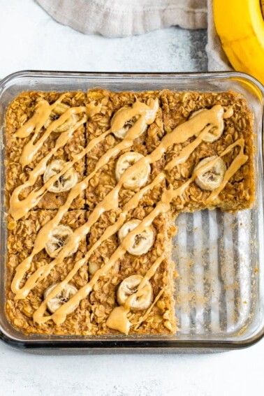 Square baking dish with peanut butter banana baked oatmeal with a slice taken out of it.