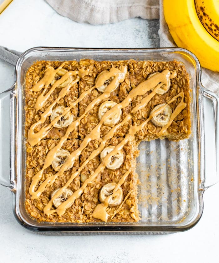 Square baking dish with peanut butter banana baked oatmeal with a slice taken out of it.