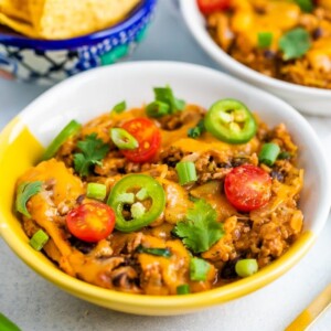 Bowl of cheesy low carb spaghetti squash taco bake topped with veggies.