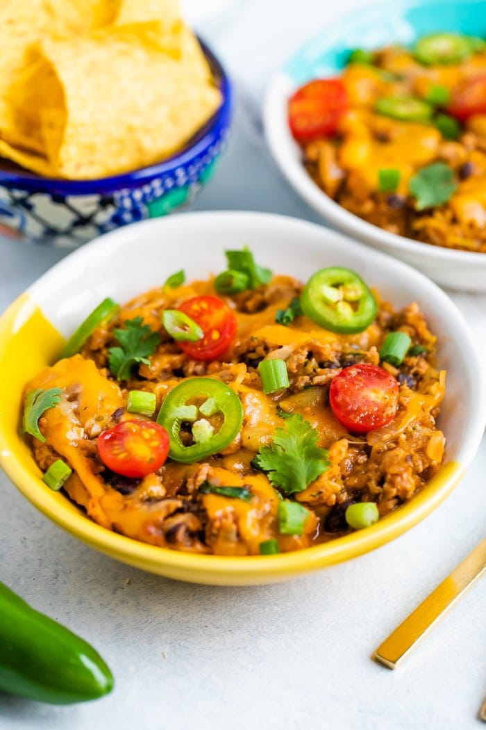 Bowl of cheesy low carb spaghetti squash taco bake topped with veggies.