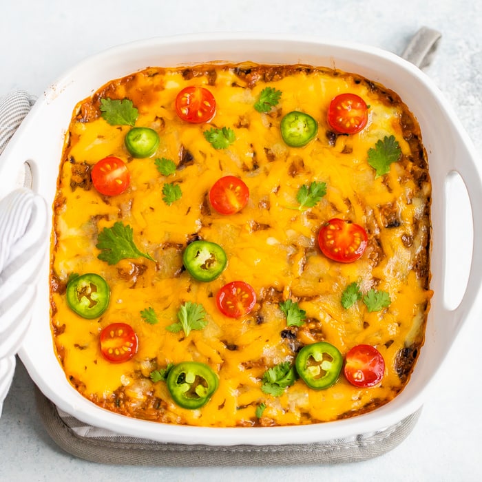 Spaghetti Squash Taco Bake in a casserole dish baked with cheese on top and topped with cilantro, tomatoes and jalapeños.