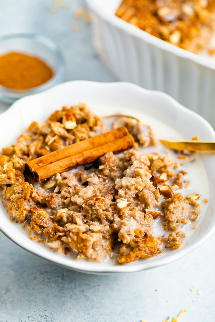 Bowl full of chai baked oatmeal topped with almond milk and a cinnamon stick.