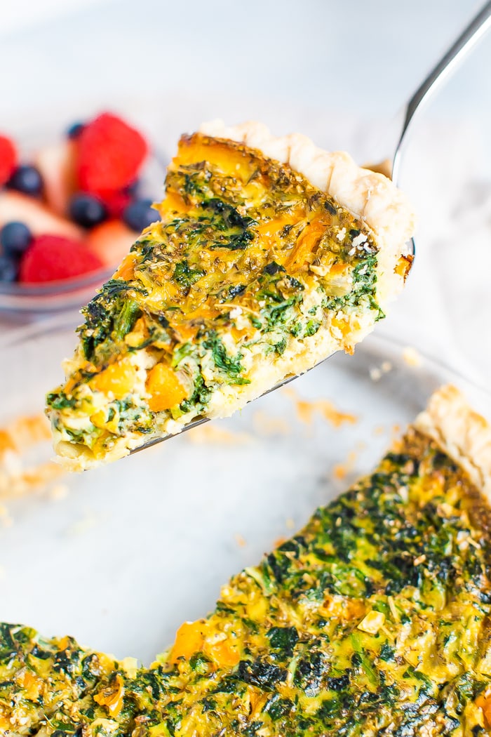 Spatula lifting up a slice of spinach and pepper quiche.