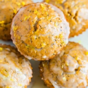 Plate with lemon poppyseed muffins topped with lemon zest and a glaze.