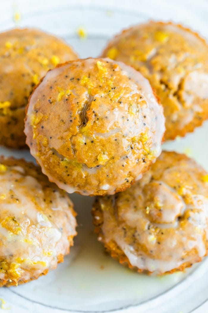 Plate piled with lemon poppyseed muffins topped with a glaze and lemon zest.