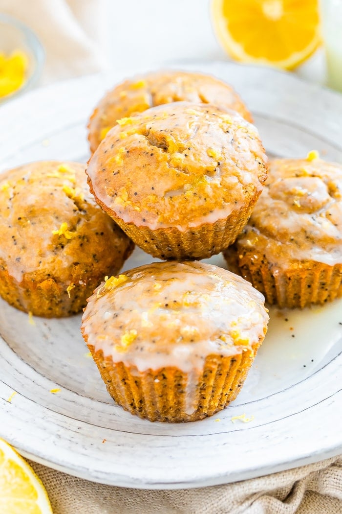 Plate with lemon poppyseed muffins topped with lemon zest and a glaze.