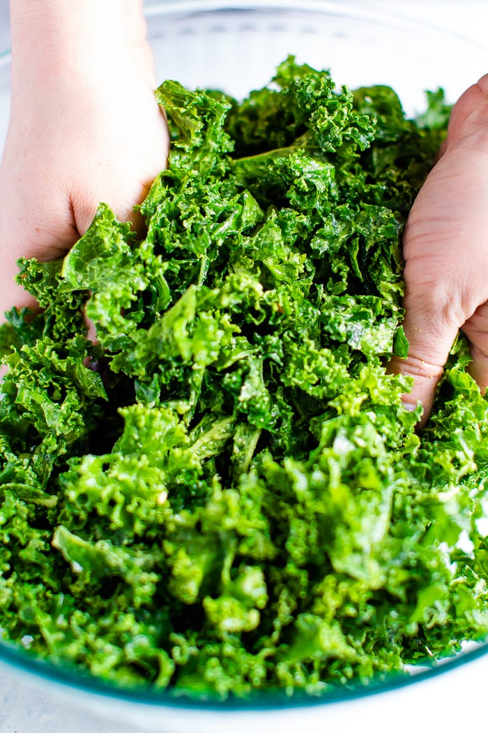 Hands massaging kale salad.