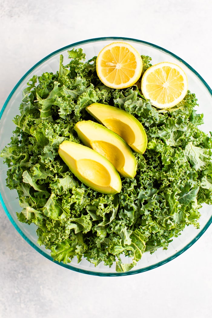 Bowl with kale and topped with lemon and avocado slices.