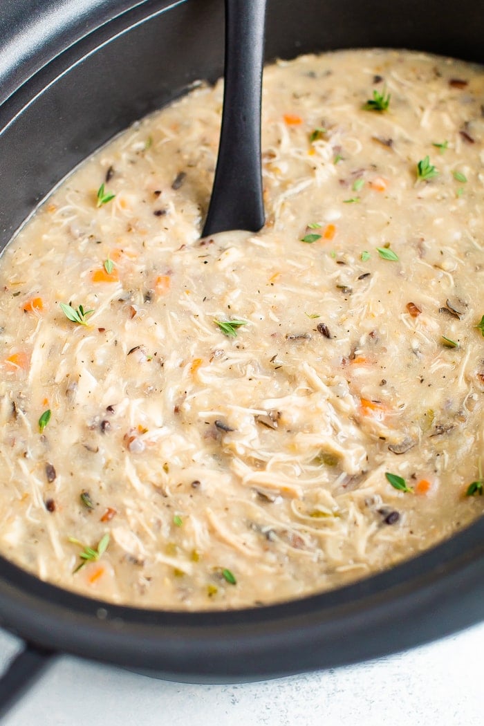 Slow cooker full of thick and creamy wild rice chicken soup. A ladle is resting in the slow cooker.