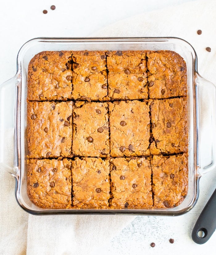 Glass square baking dish with chocolate chip blondies cup into squares.