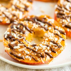 Apple samoas on a plate. Apple rings topped with caramel, chocolate drizzle and coconut flakes.