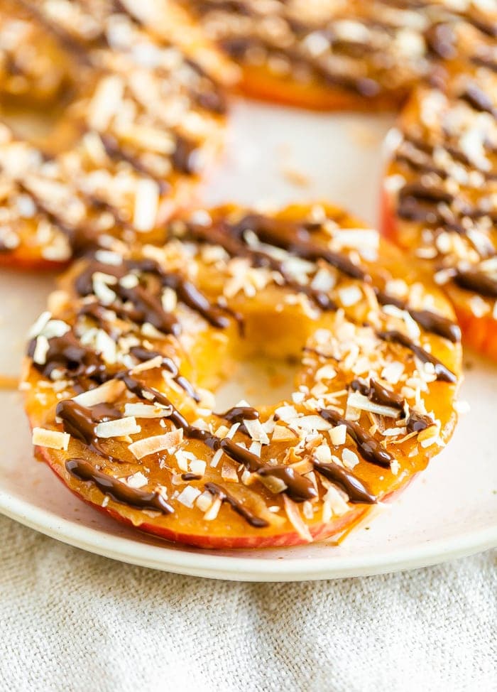 Apple samoas on a plate. Apple rings topped with caramel, chocolate drizzle and coconut flakes.