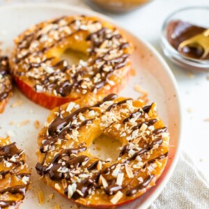 Apple samoas on a plate. Apple rings topped with caramel, chocolate drizzle and coconut flakes.