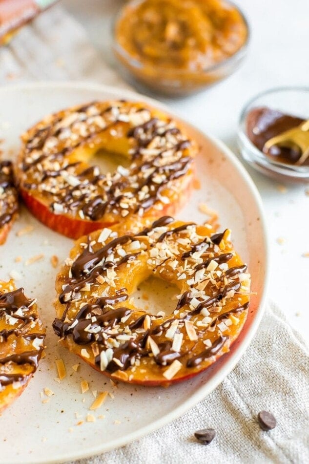 Apple samoas on a plate. Apple rings topped with caramel, chocolate drizzle and coconut flakes.