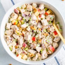 Bowl of chicken waldorf salad made with chunks of grilled chicken, chopped apple, celery, onion, herbs, walnuts and a creamy dressing.