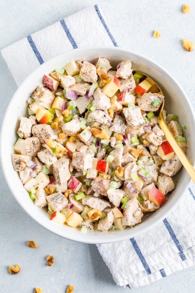 Bowl of chicken waldorf salad made with chunks of grilled chicken, chopped apple, celery, onion, herbs, walnuts and a creamy dressing.