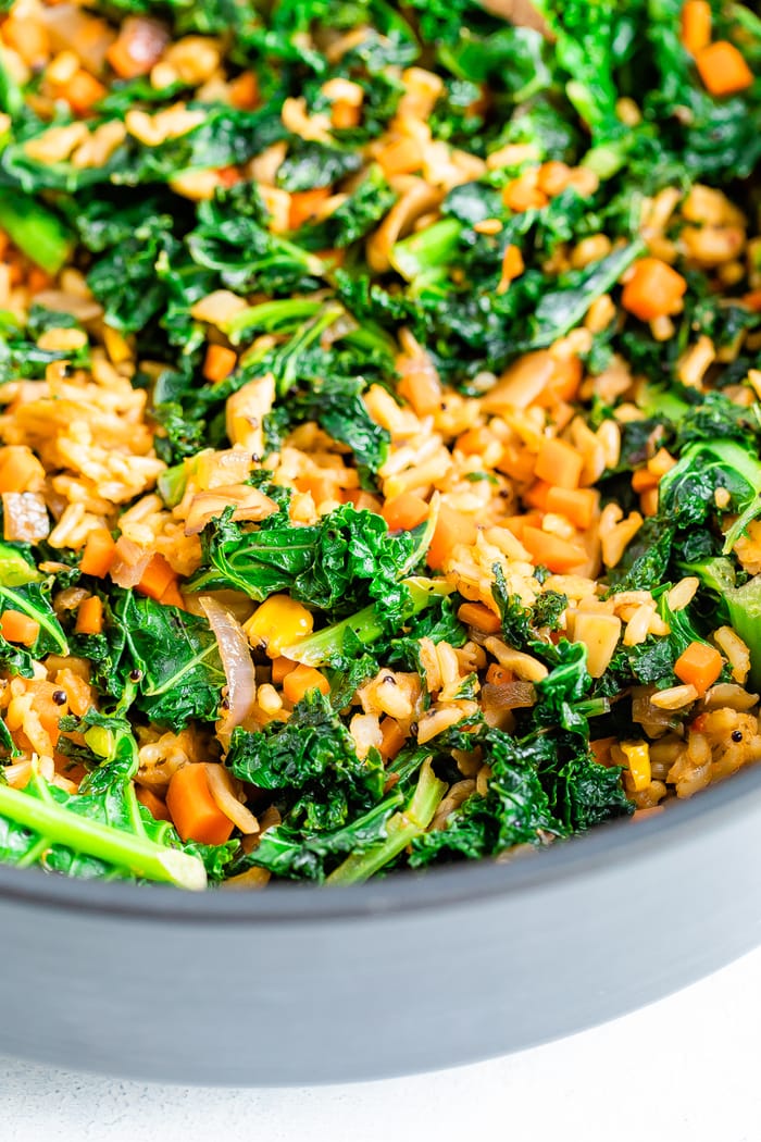 Close up of a skillet with cooked kale, rice and veggies.