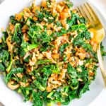 Bowl of sautéed kale, mushrooms and Spanish rice with a gold fork.