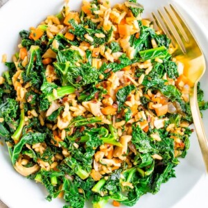 Bowl of sautéed kale, mushrooms and Spanish rice with a gold fork.