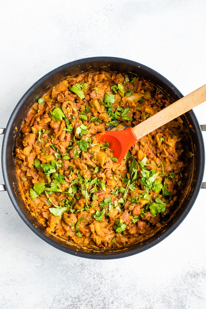 Pot filled with red beans and topped with herbs.