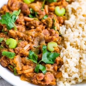 Plate of red beans and rice topped with fresh celery ad parsley.